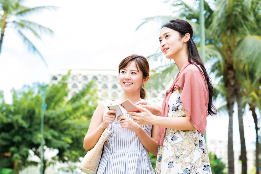 ハワイの街中でスマホを触る女性旅行者